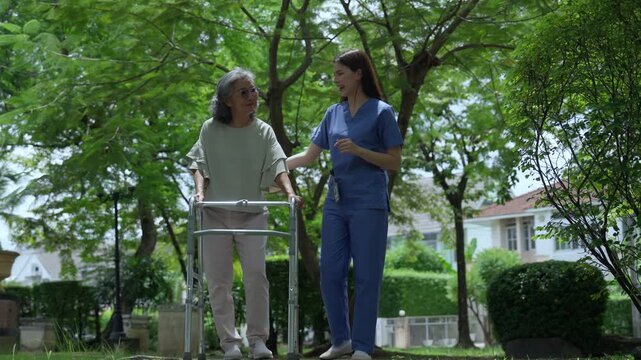 The caregiver is helping an elderly Asian woman rehabilitate her walking and monitor her condition after she underwent knee surgery, using treatment information from her doctor.