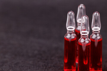 Red vitamin B12 ampoules on black background representing injection wellness and therapy.