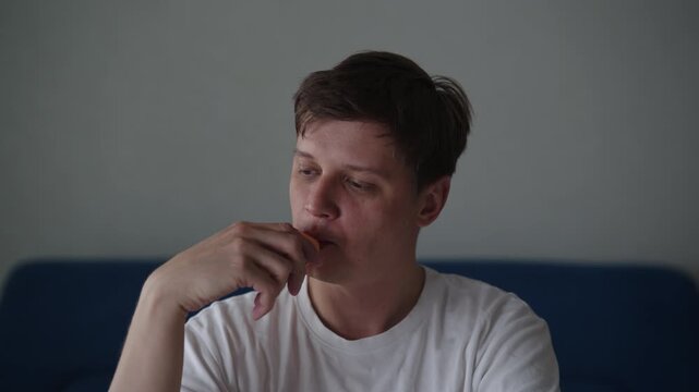 Portrait of pensive young man exhaling vapor from electronic cigarette, highlighting modern habit of vaping and implications for individual lifestyle and potential health considerations, slow motion.