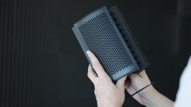 Person holding black acoustic foam panel, creating soundproof environment for microphone, enhancing audio recording quality and reducing reverb in professional studio setting, close-up, slow motion.