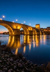 Fototapeta premium A stunning stone bridge reflects beautifully in the calm water at twilight, bathed in warm, golden light.