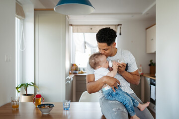 Father bottle feeding a small toddler son.