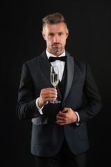 Elegant tuxedo man hold glass of champagne isolated on black. Celebrating success. Cheers. Mature man has formal look. Celebrate with champagne. Cheering and celebrating