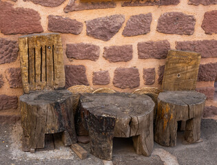 Pared de piedra rústica y tres  tocones de madera que sirven como elementos decorativos o asientos.