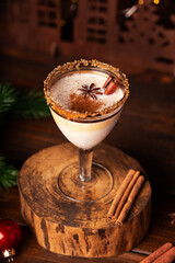 Elegant glass of Holiday eggnog cocktail with dark rum and milk garnished with nutmeg on dark Christmas background, vertical photo