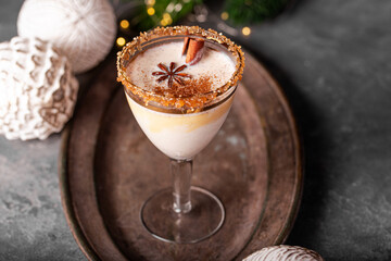 Elegant glass of Holiday eggnog cocktail with dark rum and milk garnished with nutmeg on Christmas background