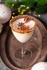 Elegant glass of Holiday eggnog cocktail with dark rum and milk garnished with nutmeg on Christmas background, vertical photo