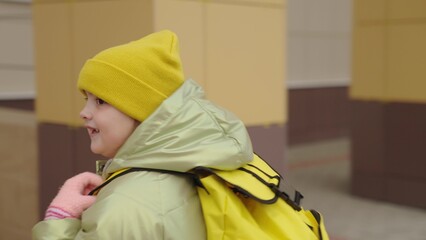 girl with a school backpack runs to school, child with a bag behind sleeping bag rushes to school,...
