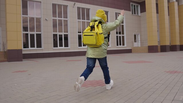slow motion. schoolgirl with backpack hurries lesson on an autumn day. childhood education concept. school run kid girls. get back school quickly. children run through school yard education building. - Powered by Adobe