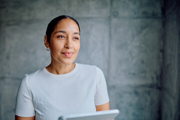 Confident businesswoman smiling in a portrait, holding a modern digital tablet, representing...