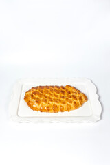 Golden fish-shaped pie on white plate, top view.