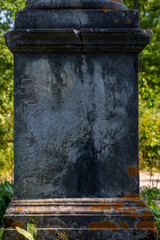 Weathered stone monument base with moss and cracks in sunlight
