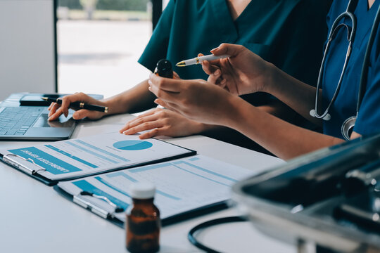 Medical team meeting analyzing blood test results in hospital laboratory. Doctors and scientists in lab coats are having a discussion about blood test result, holding test tubes and taking notes.