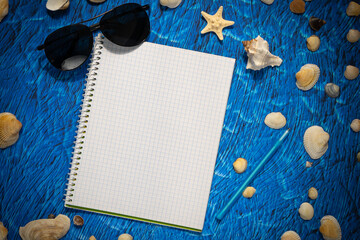 flat lay on blue background blank notebook copy space. summer plans concept