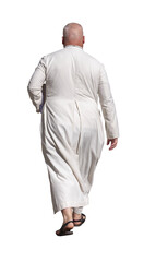 Homme d’église chauve vu de dos marchant en été, portant une longue robe blanche religieuse et des sandales noires, avançant l avec une démarche calme et sereine