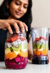 Indian woman joyfully preparing colorful fruit smoothie
