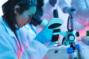 Female scientist researching using microscope in laboratory