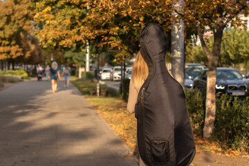Young woman walking with her guitar in the park