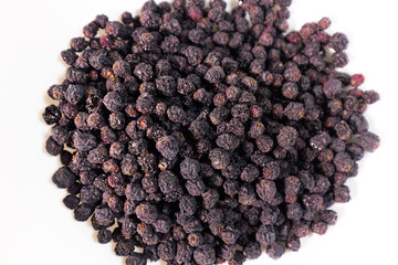 Detailed macro view of a dense, wrinkled, dark, dried  berries pile showing texture and natural variations. White background.