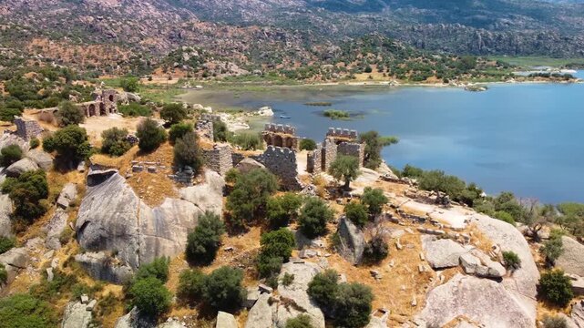 aerial perspective captures the historical ruins of Herakleia by Latmos nestled along the tranquil shores of Lake Bafa in Turkey. This footage showcases the stunning natural beauty of the lake, surrou