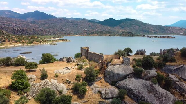 aerial drone shot showcasing the serene beauty of Bafa Lake, a significant nature reserve in southwestern Turkey, alongside the captivating ruins of the ancient city of Heraclea by Latmus. This footag