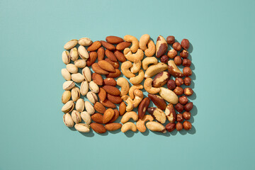 Assorted nuts arranged on a pastel blue background.