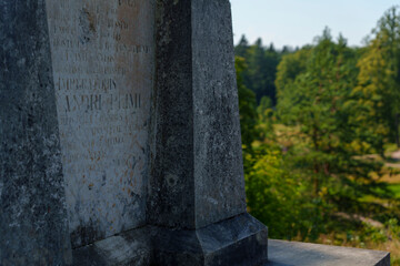 Close-up of old stone monument with forest in the background