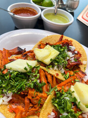 Mexican tacos al pastor with pineapple, onion, and cilantro served on corn tortillas