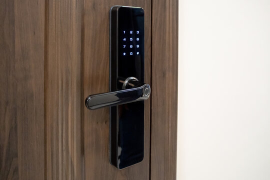 Smart door lock with keypad and hand entering code. Electronic lock system for secure access control. Real photo