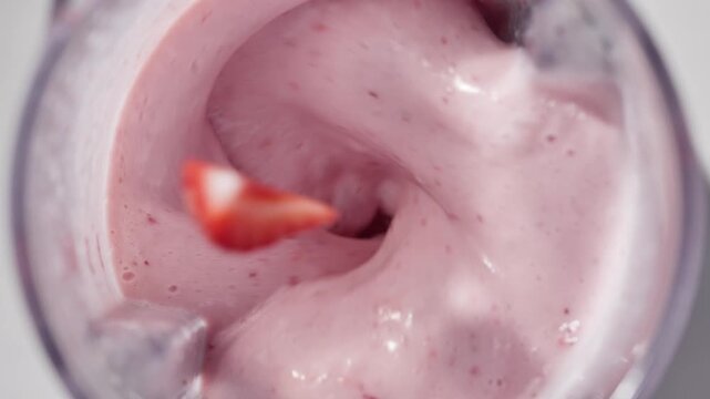 Strawberry and banana pink milkshake blended in blender with splashes. top view. slow motion. Healthy protein smoothie drink concept , food closeup