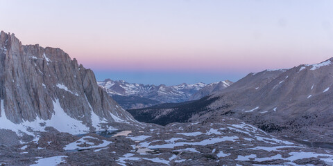Aerial view of snow capped mountains and valley under a pastel colored sky at dusk or dawn time © Rodrigo