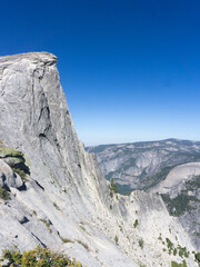A view of half dome in yosemite national park under a clear blue sky on a sunny day with mountains