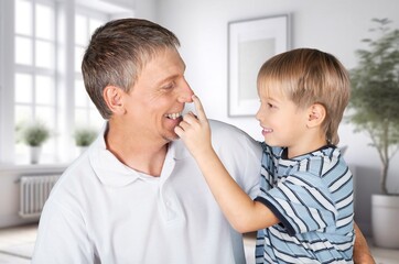 Happy young father hugging son in living room.