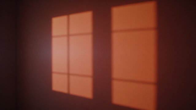 Window light pattern on wall during sunset casts grid like design indoors.