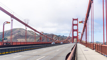 The golden gate bridge with cars on the road and hills in the background on a cloudy day in san francisco