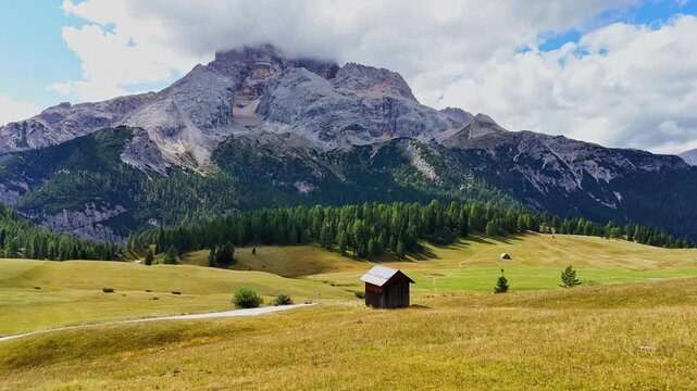Beautiful landscape in Dolomites, Italy.  Malga Prato Piazza meadow and big mountain summit and ridge. South Tyrol region in Italy. Trekking and bike road in Italy Dolomites. Wooden cabin hut.