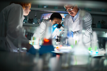 Multi-ethnic group of chemists doing research in modern laboratory. Pretty young woman in...