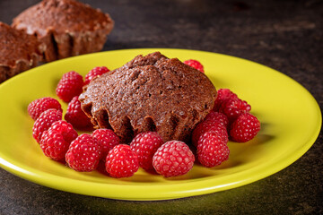 Delicious muffin on a bright green plate surrounded by fresh raspberries