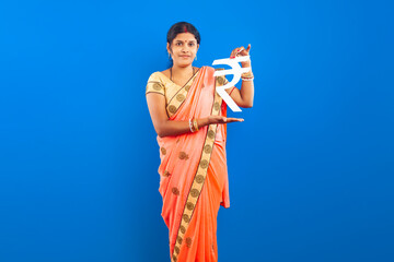 Indian woman in traditional saree holding rupee currency symbol on blue background