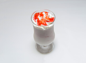 strawberry smoothie with whipped cream, cheese and syrup topping served in glass on white background
