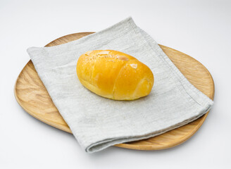 Salted Caramel Almond Bread Roll on Wood Plate and Napkin on white background side view