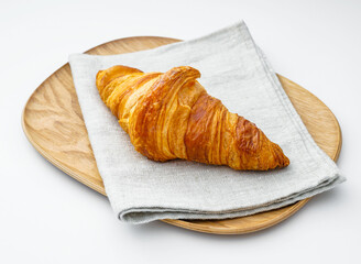 Baked Golden Croissant on Wooden Plate and Napkin Flaky French Pastry on White Background