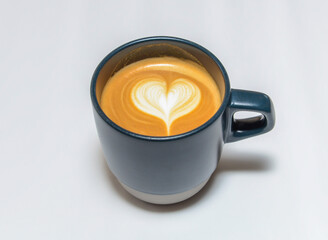 Hot Milk Tea or Hazelnut Latte with Perfect Heart Latte Art in a Dark Blue Mug isolated on white background top view