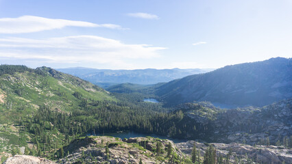 Aerial view of a mountain valley with a lake and a forest under a clear blue sky during daytime