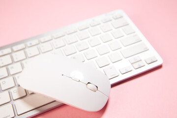 white mouse on a pink keyboard with a pink background