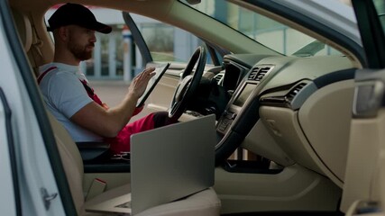 Mechanic analyzing vehicle performance data on laptop inside car, showcasing modern technology and automotive diagnostics in a well-lit interior environment - Powered by Adobe