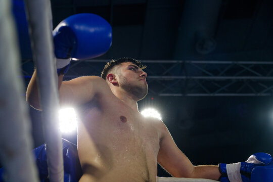 Cornered boxer receives strategic advice from trainer during intense bout.