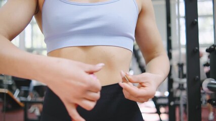 Woman measuring waist size in gym while focusing on fitness goals and health improvements during workout session
