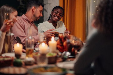 Friends enjoying thanksgiving dinner with roasted turkey and candles