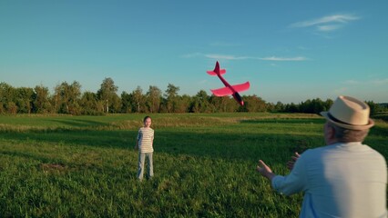 Little daughter plays with toy airplane with her dad on green lawn in park. Happy family. Carefree dad plays with daughter in summer park, Father's Day. Children's leisure. Family holiday, parent kid